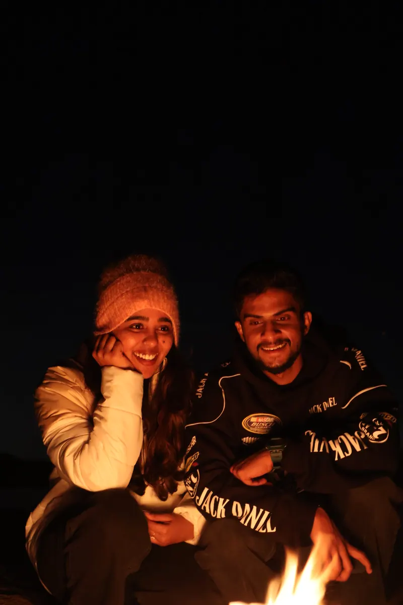 Alka and Jishnu by a campfire at night